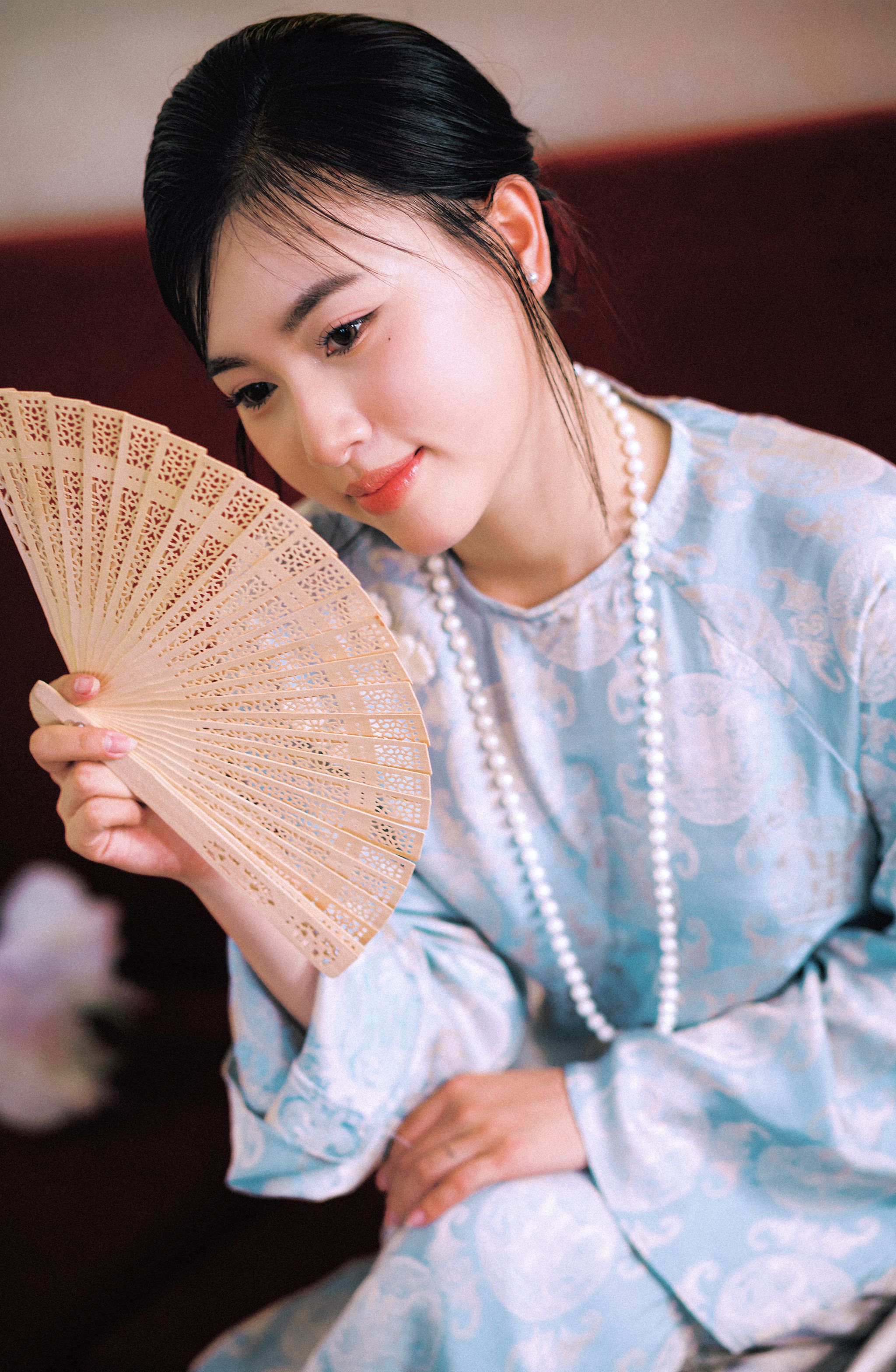 Beautiful portrait of an Asian woman holding a fan in traditional attire.