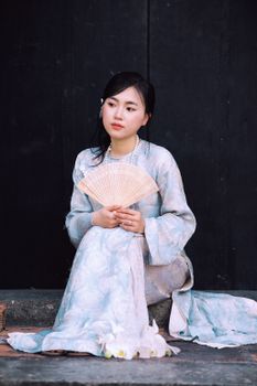 Portrait of a Vietnamese woman in Áo Dài holding a fan in Sa Đéc, Vietnam.