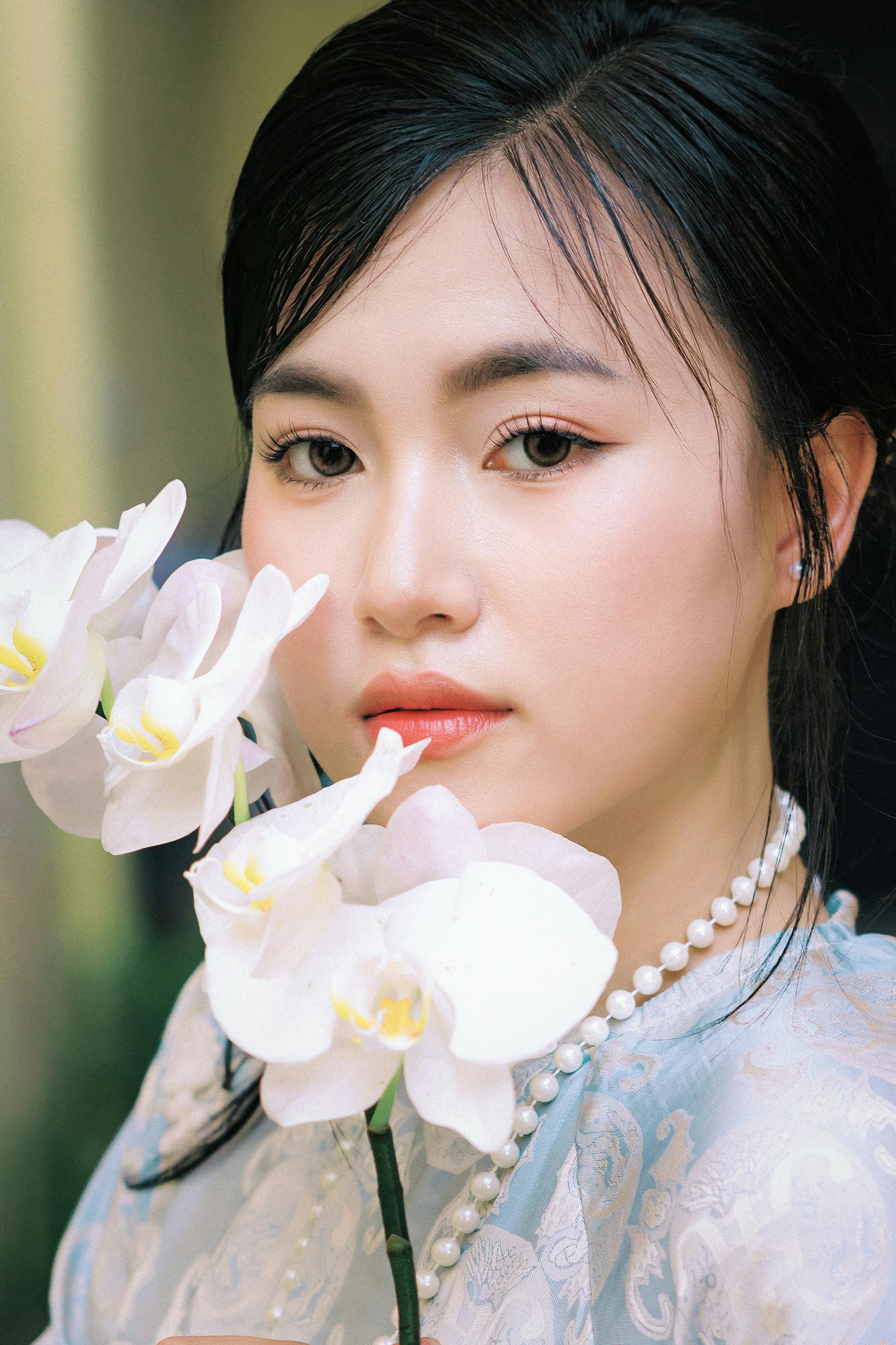Close-up of a woman holding orchids, showcasing Vietnamese beauty.
