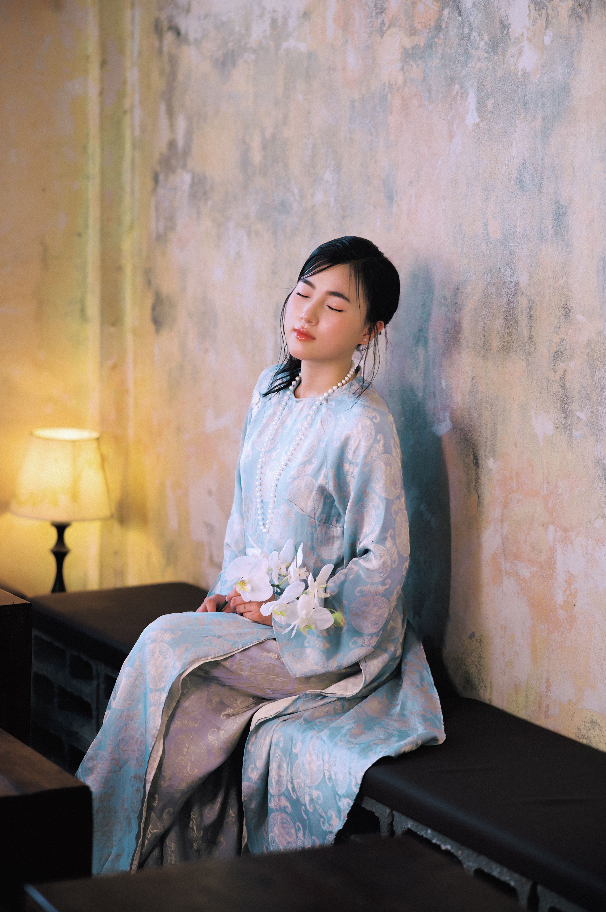 A serene portrait of a woman in traditional Vietnamese attire, indoors.