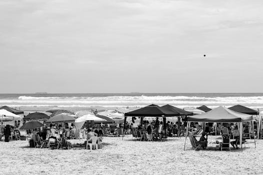 Crowded beach with tents and people enjoying the summer day in black and white.