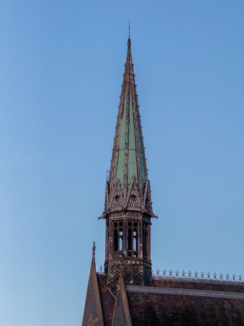 Free Close-up of a historic Gothic church spire with a clear blue sky backdrop, showcasing intricate architecture. Stock Photo
