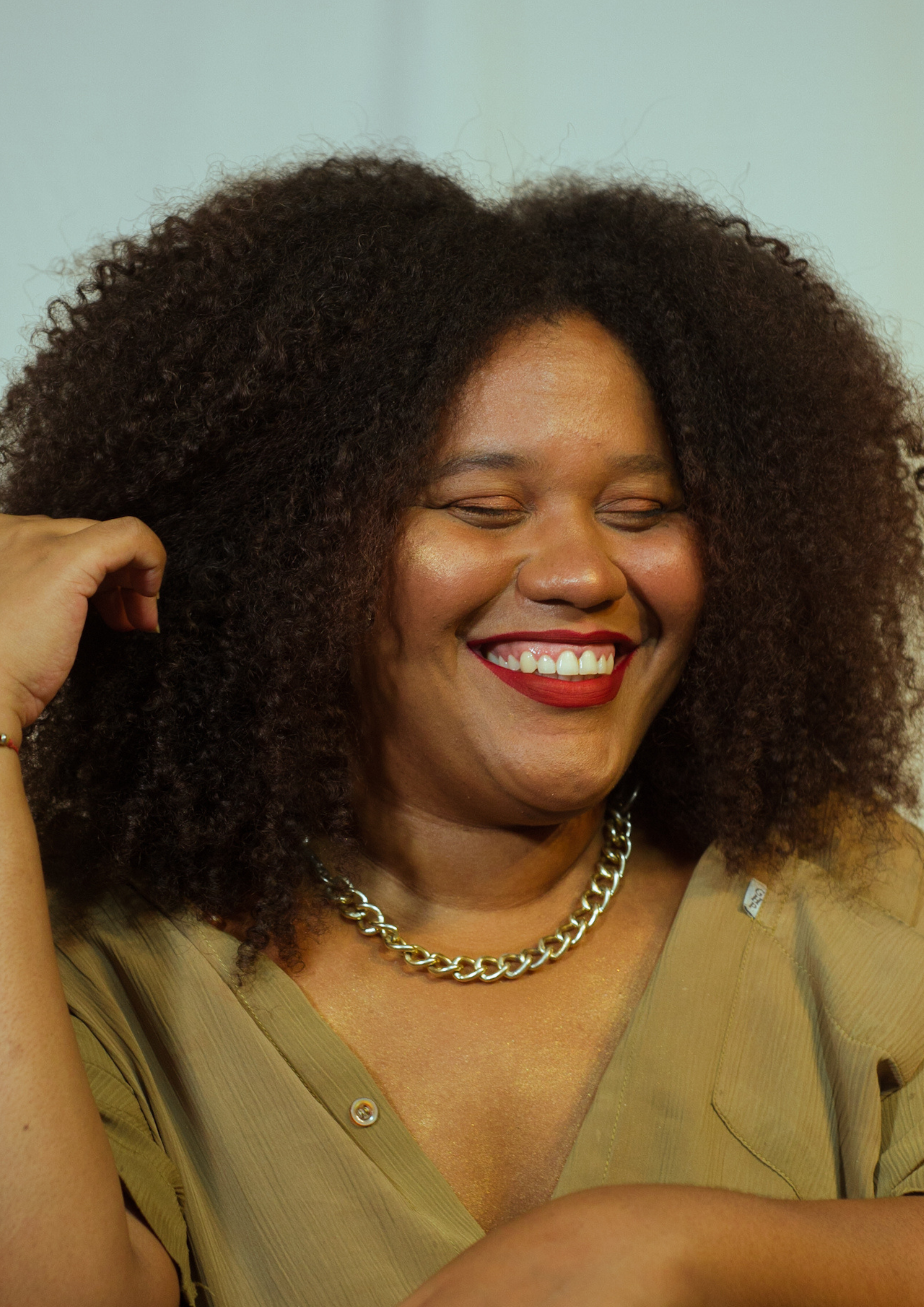 Close-up of a cheerful woman with curly hair smiling joyfully indoors.