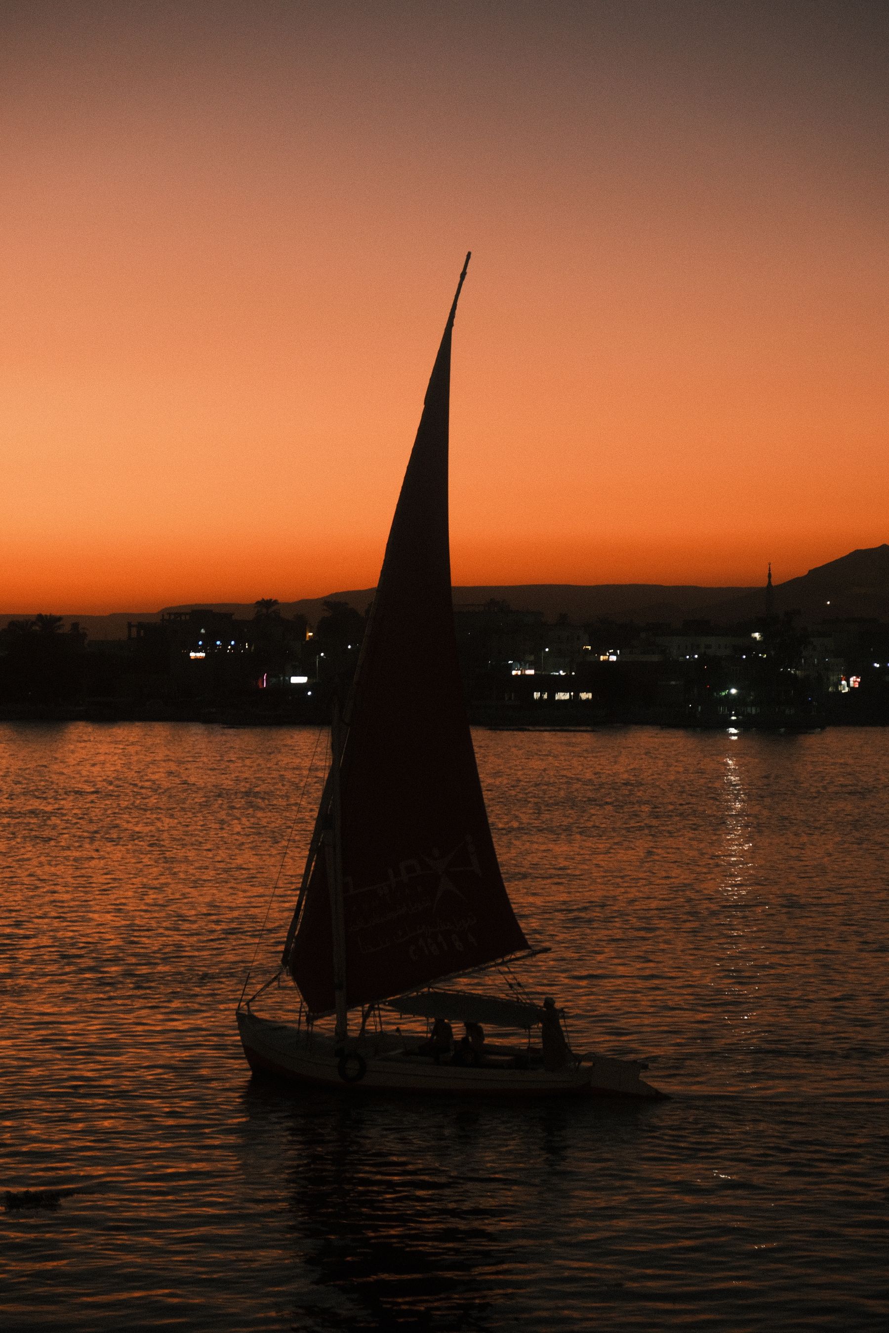 Een felucca vaart bij zonsondergang over de Nijl in Luxor