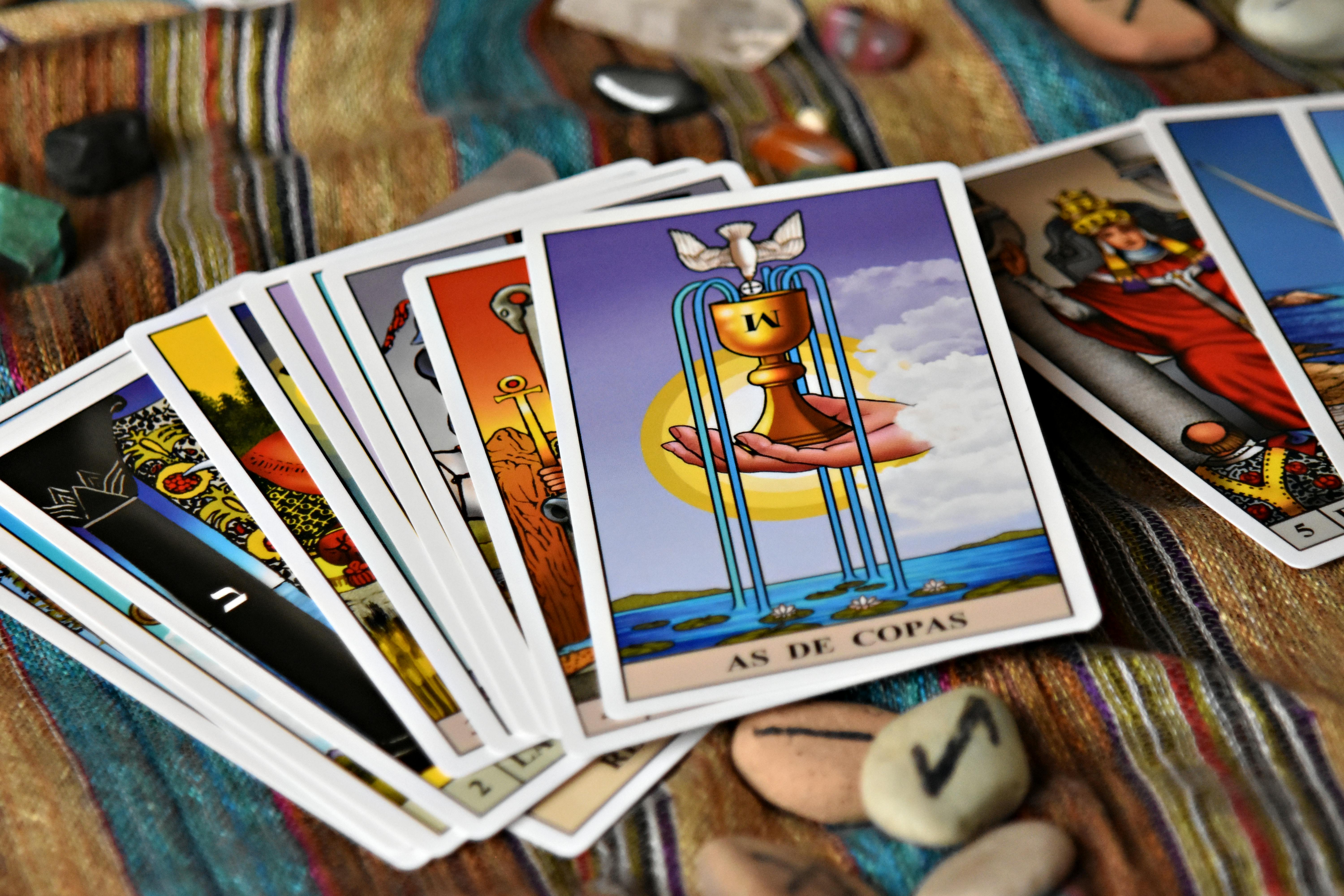 A set of tarot cards spread on a colorful fabric with crystal stones, reflecting mysticism.