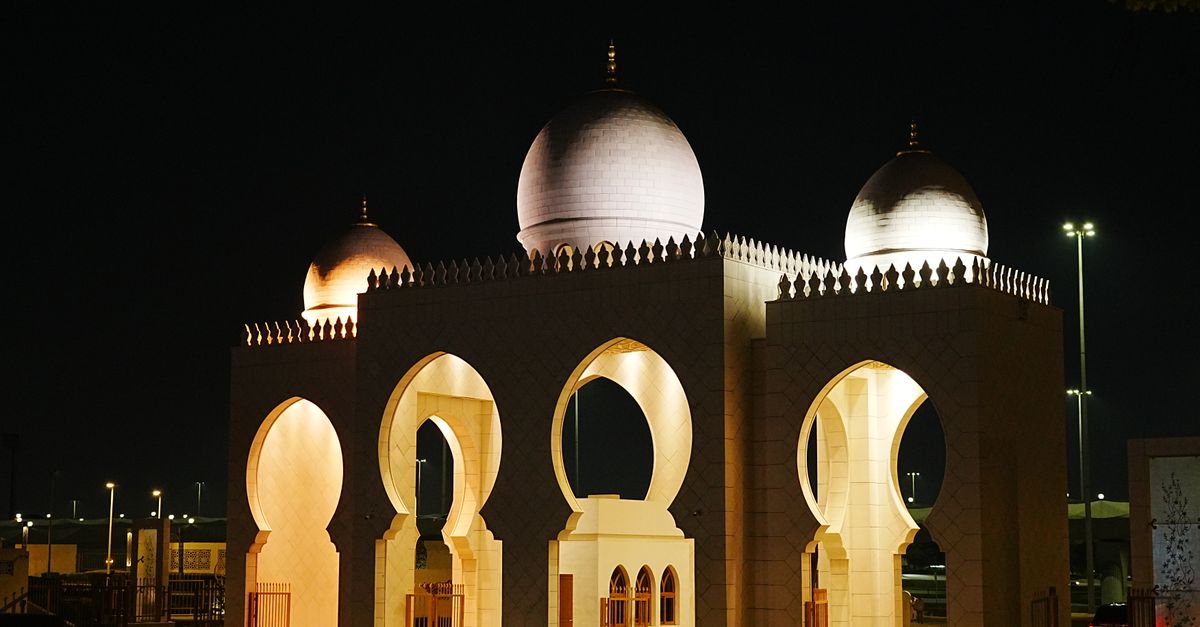 Illuminated domed structure in Abu Dhabi captured at night, showcasing intricate architectural detai