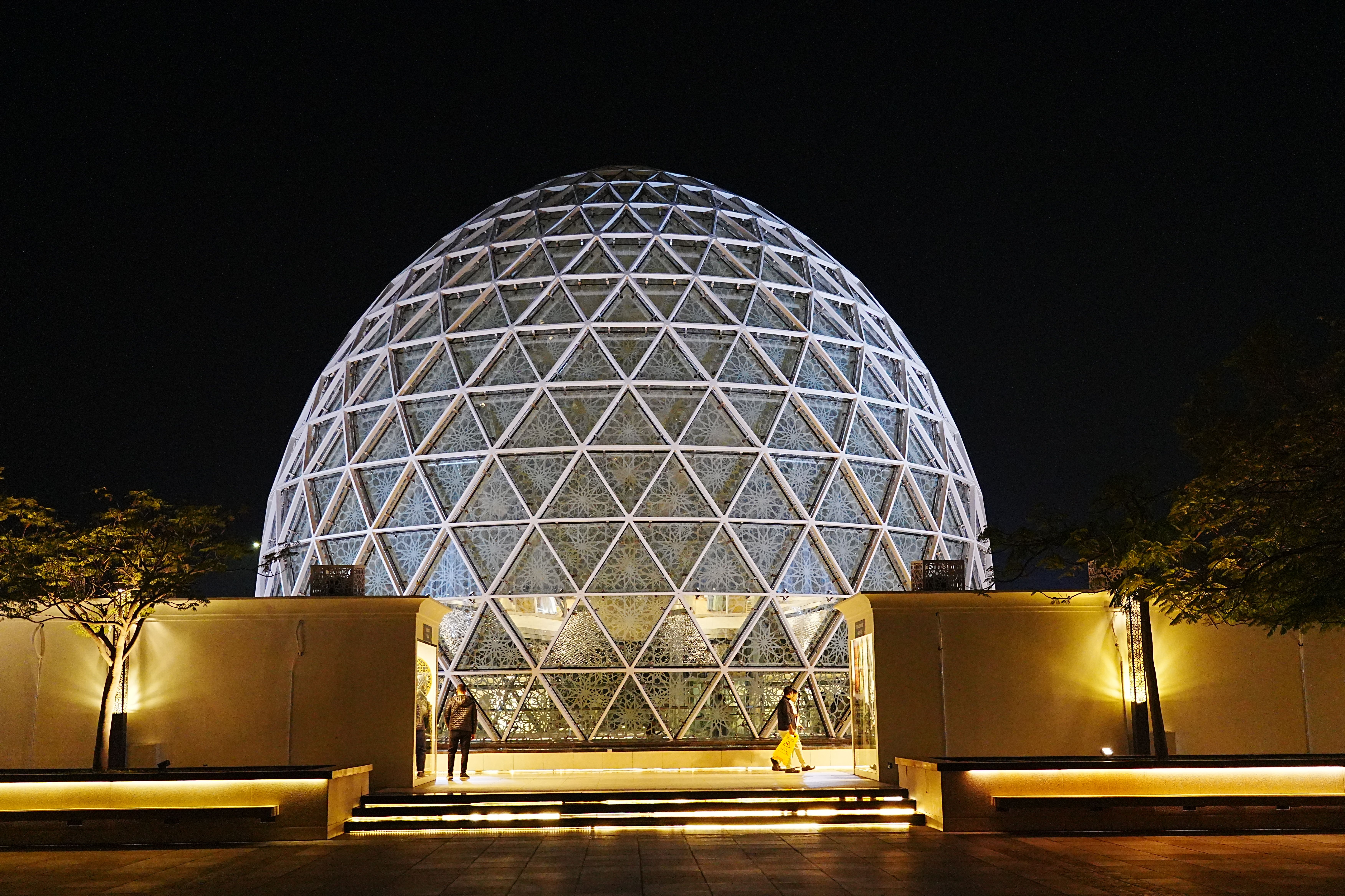 Illuminated geometric dome structure in Abu Dhabi, showcasing modern architecture at night.