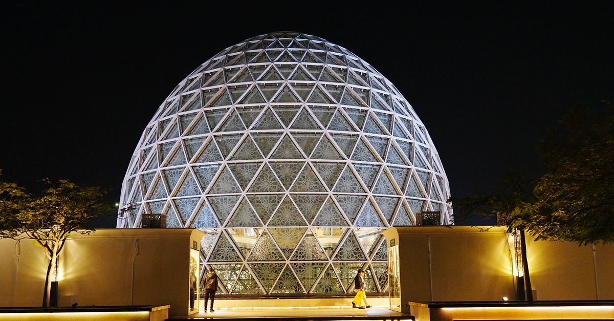 Illuminated geometric dome structure in Abu Dhabi, showcasing modern architecture at night.