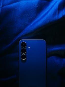 Artistic close-up of a blue smartphone placed on blue fabric, highlighting design aesthetics.