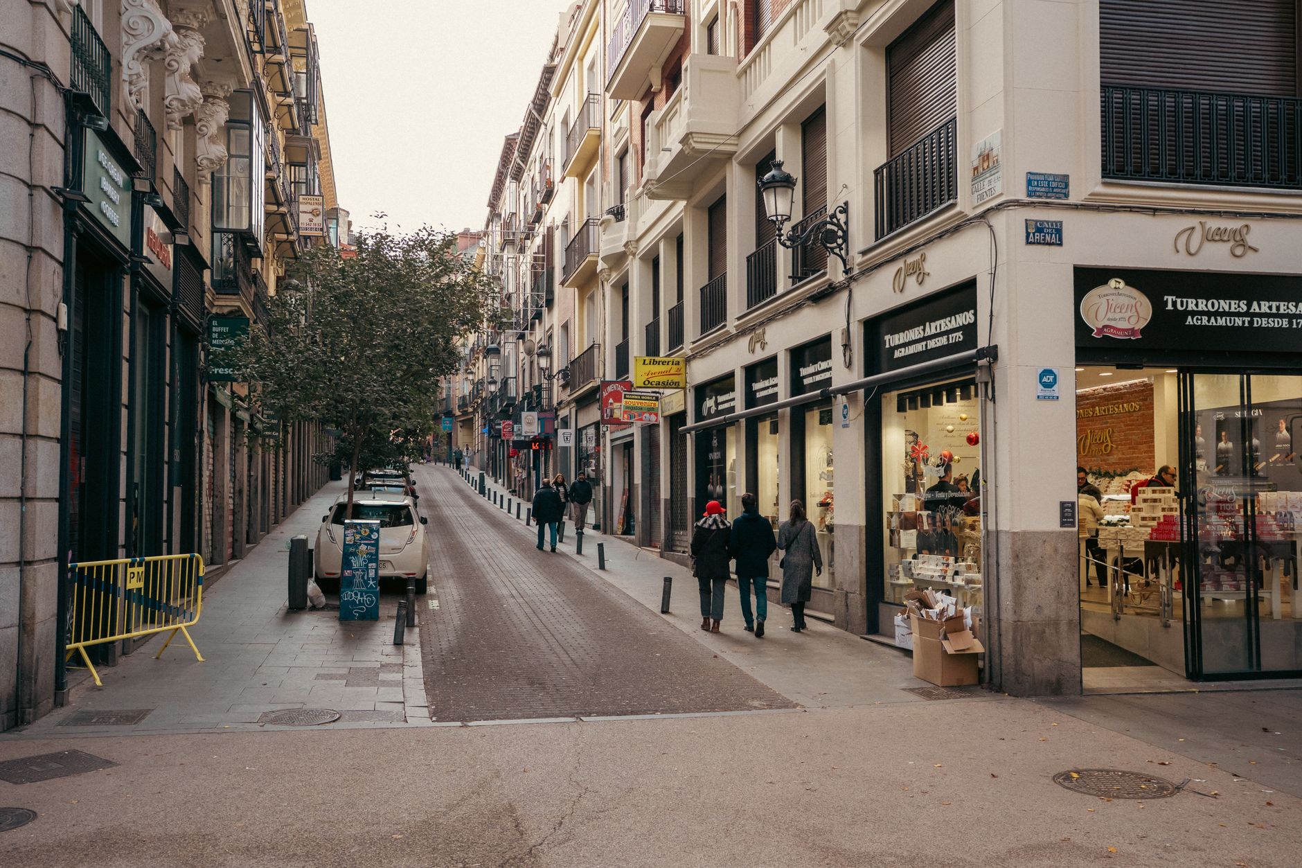 Urban view of Calle de Arenal in Madrid with pedestrians and shops on a bustling street.