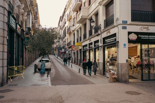 Urban view of Calle de Arenal in Madrid with pedestrians and shops on a bustling street.