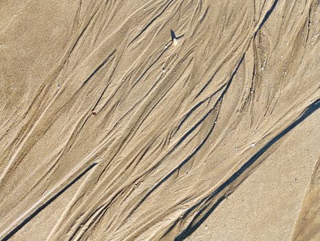 Close-up of intricate sand patterns created by water flow on a beach in Casablanca, Morocco.