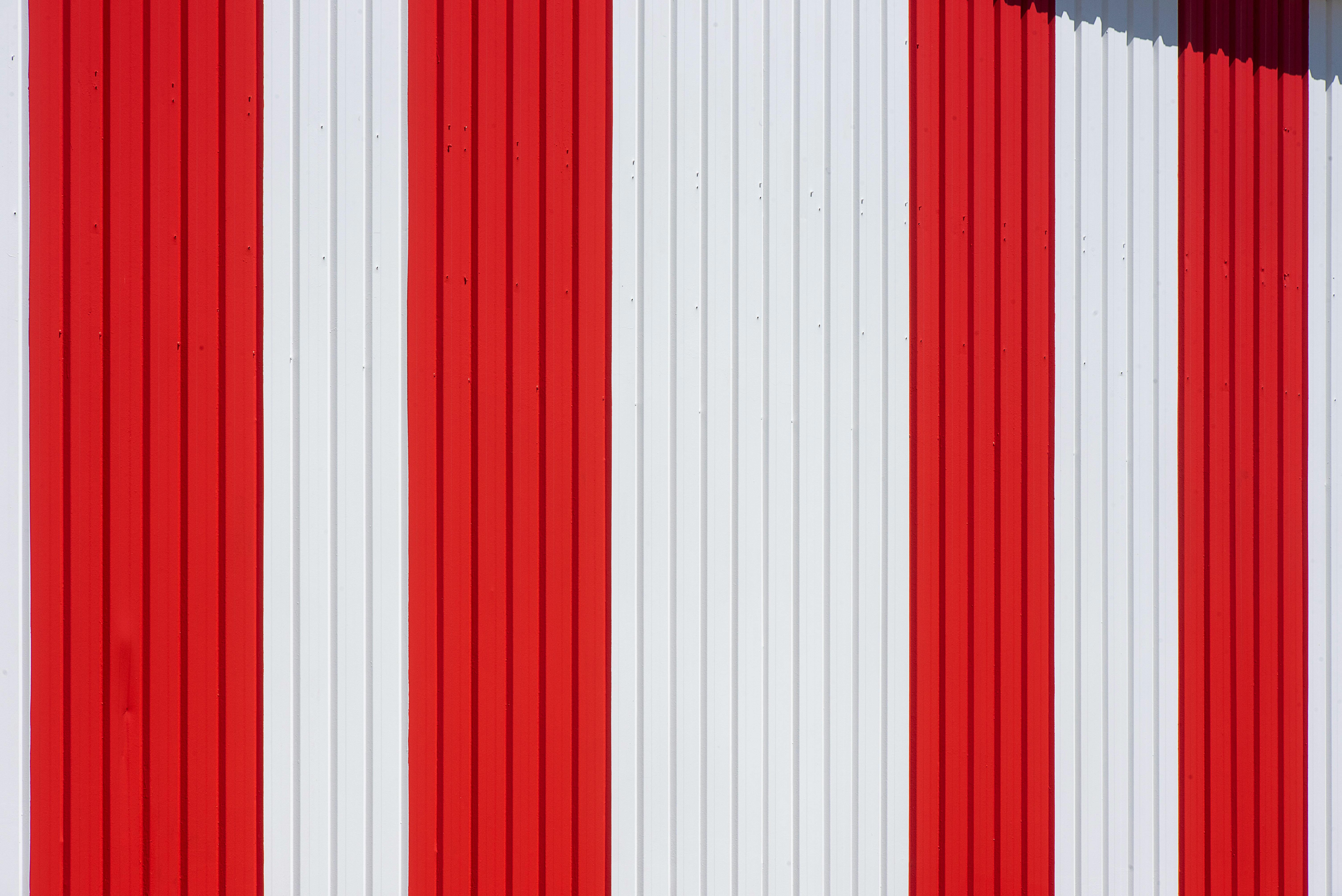 Kostenlos Nahaufnahme von vertikalen roten und weißen Streifen auf einer Wellblechwand. Stock-Foto