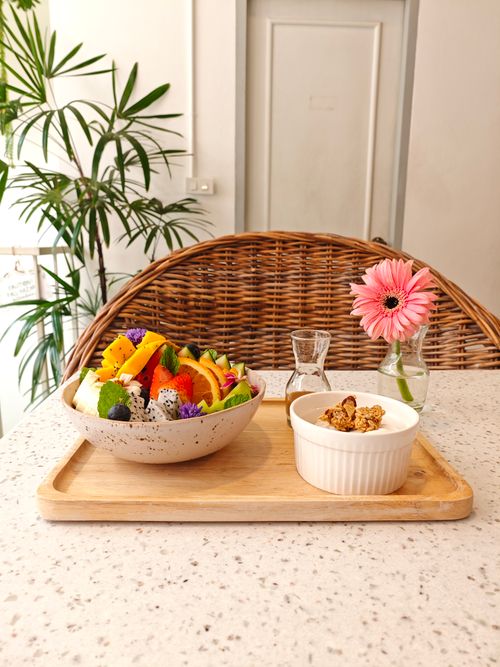 Free Colorful fruit bowl with yogurt and granola on a wooden tray in a cozy cafe setting. Stock Photo