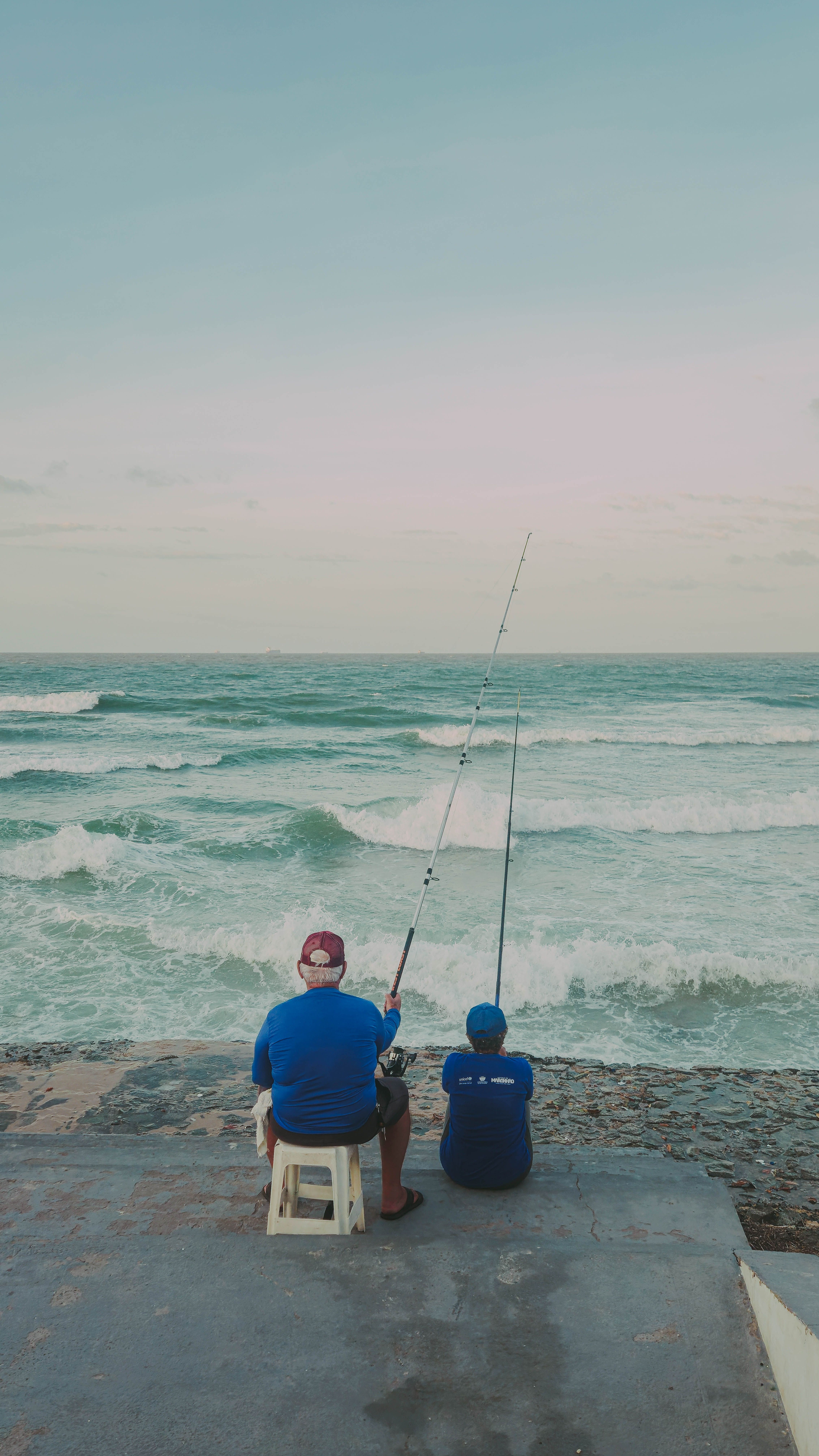 Two men fishing by the ocean in Maranhão, Brazil. Peaceful coastal scene.