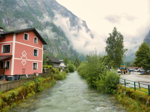 Free Charming alpine scene with mountain river and vibrant houses. Perfect for nature and travel themes. Stock Photo