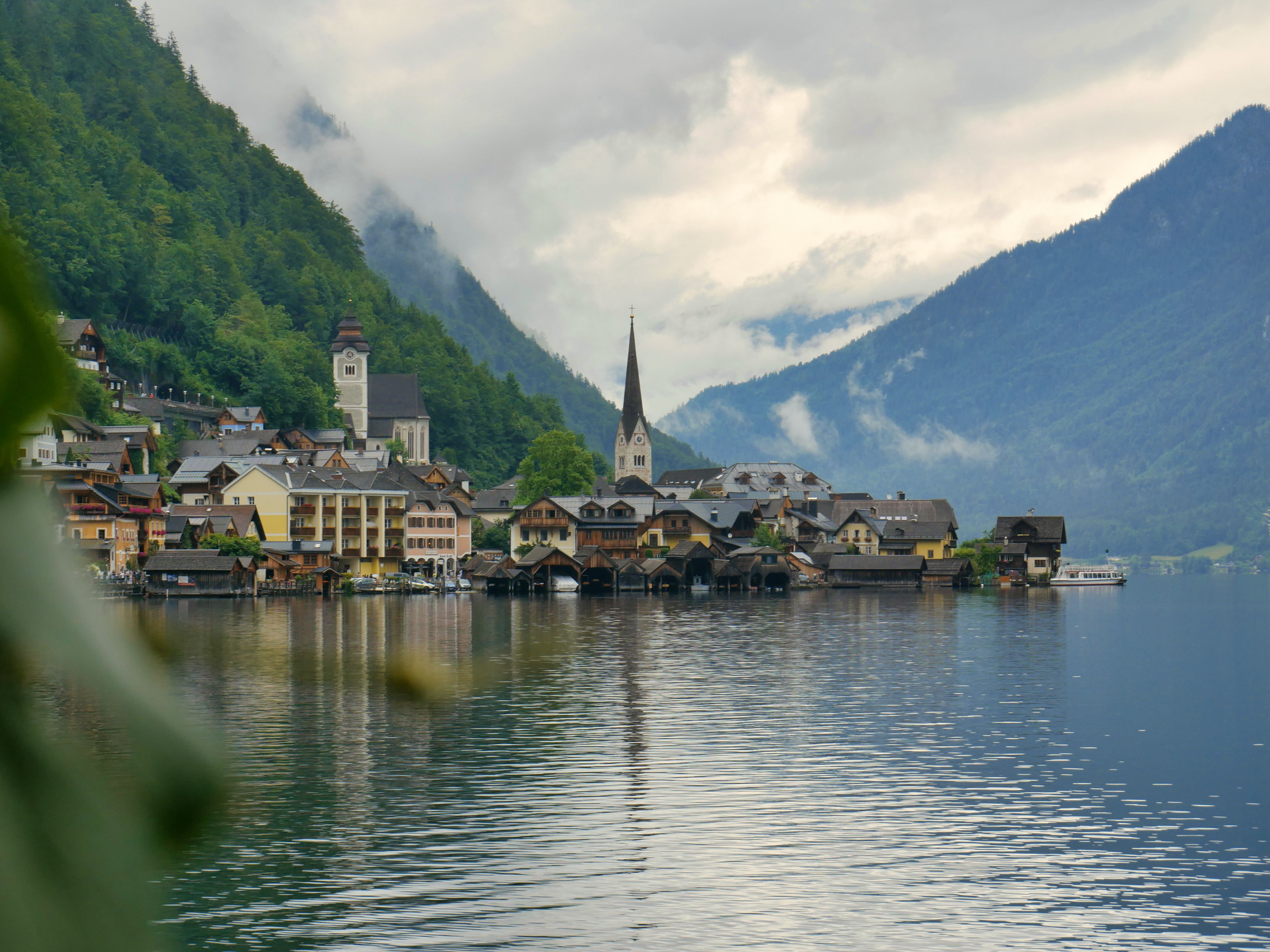 Peaceful view of Hallstatt village with alpine backdrop reflected in calm lake.