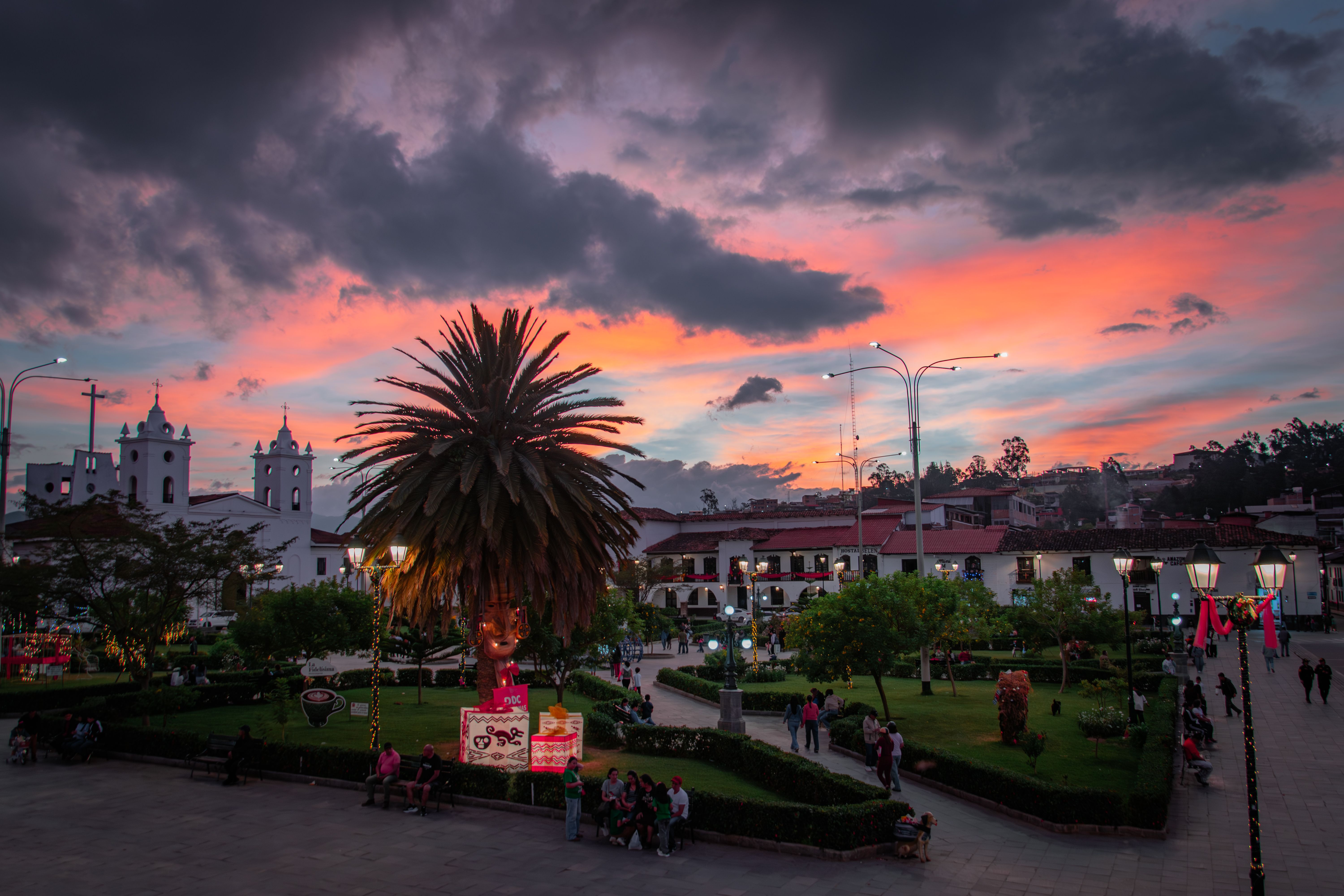 Evening on a plaza in a La Paz department town with people walking under the church facade