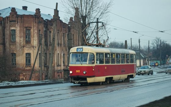 Red and cream tram number 27 travels on a rainy street in historic Kharkiv, Ukraine.