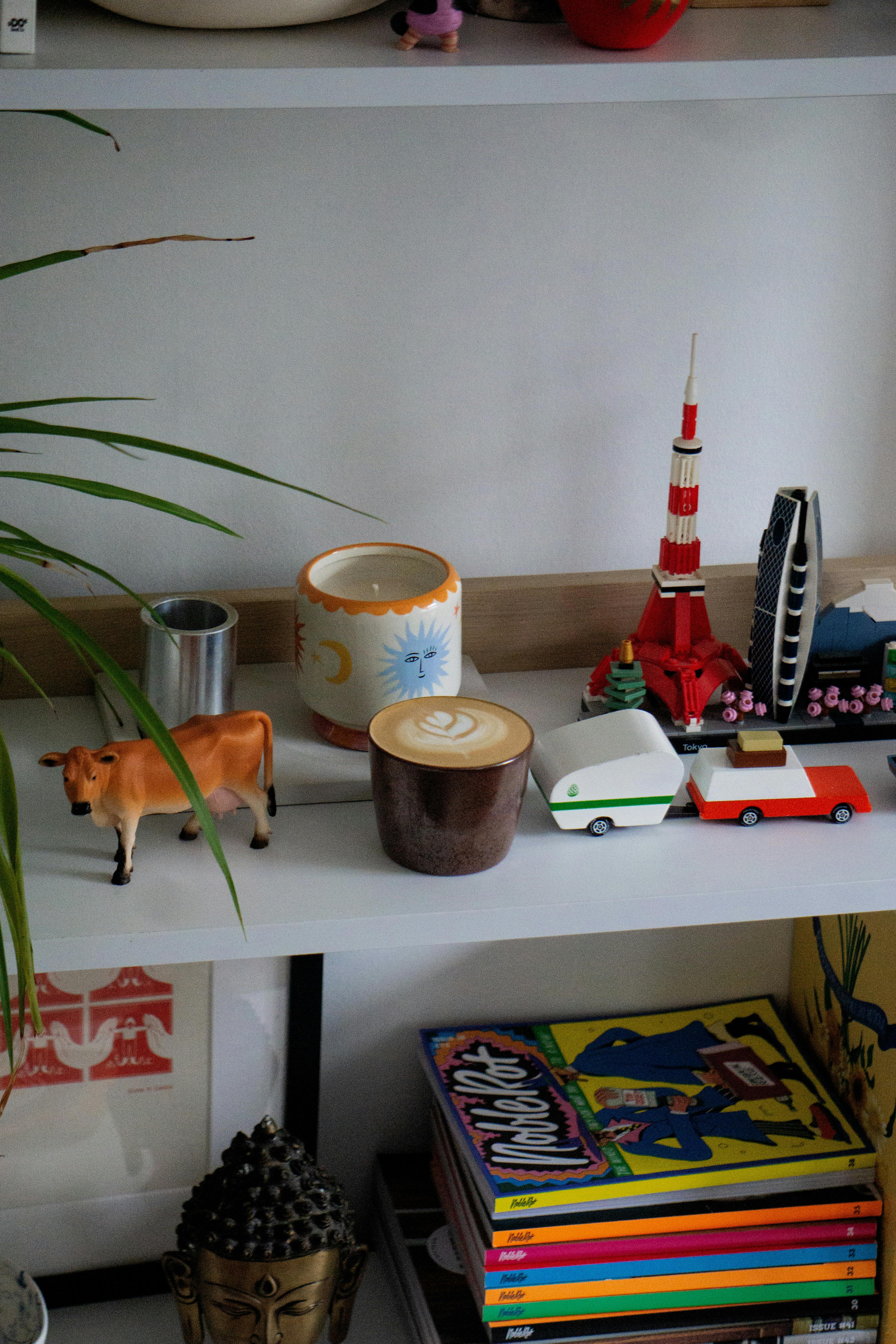 Bezpłatne Półka z kawą, modelami budynków, książkami i eklektyczną dekoracją. Zdjęcie z galerii