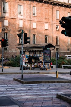 A city kiosk surrounded by traffic lights and a brick building background.