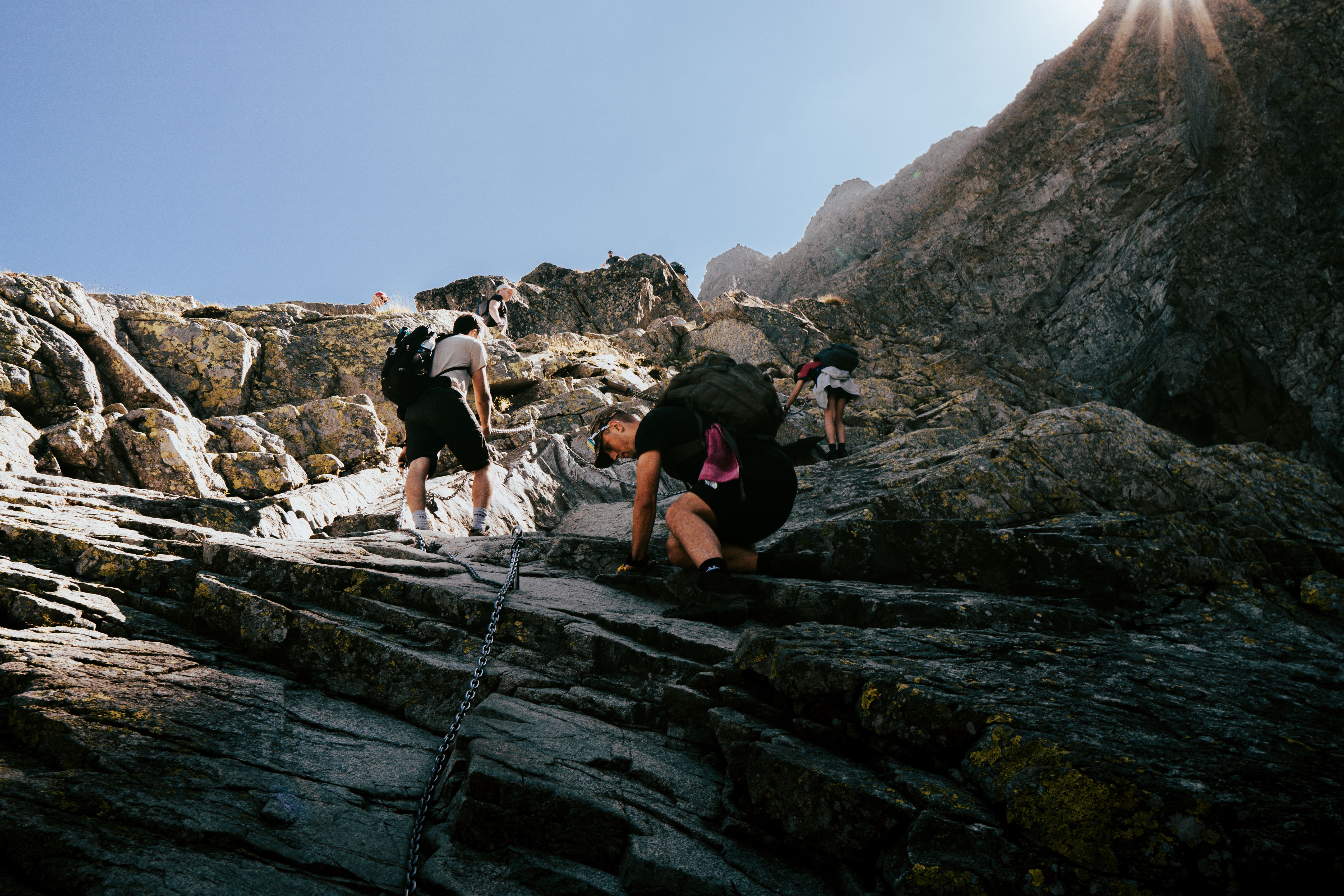 Hikers climbing a steep rocky mountain slope on a technical scrambling route