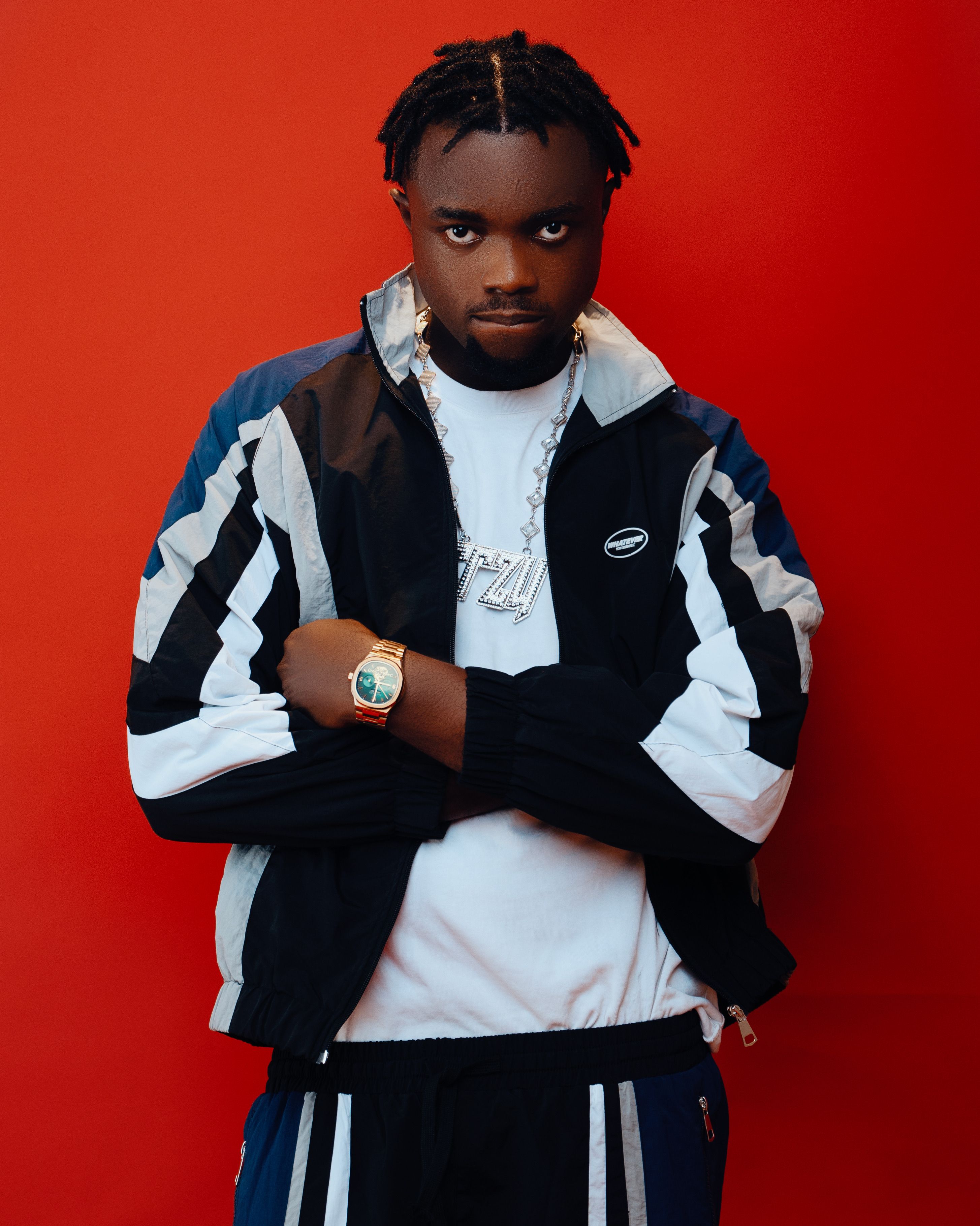 Stylish young adult posing confidently in trendy sporty attire against a red backdrop.