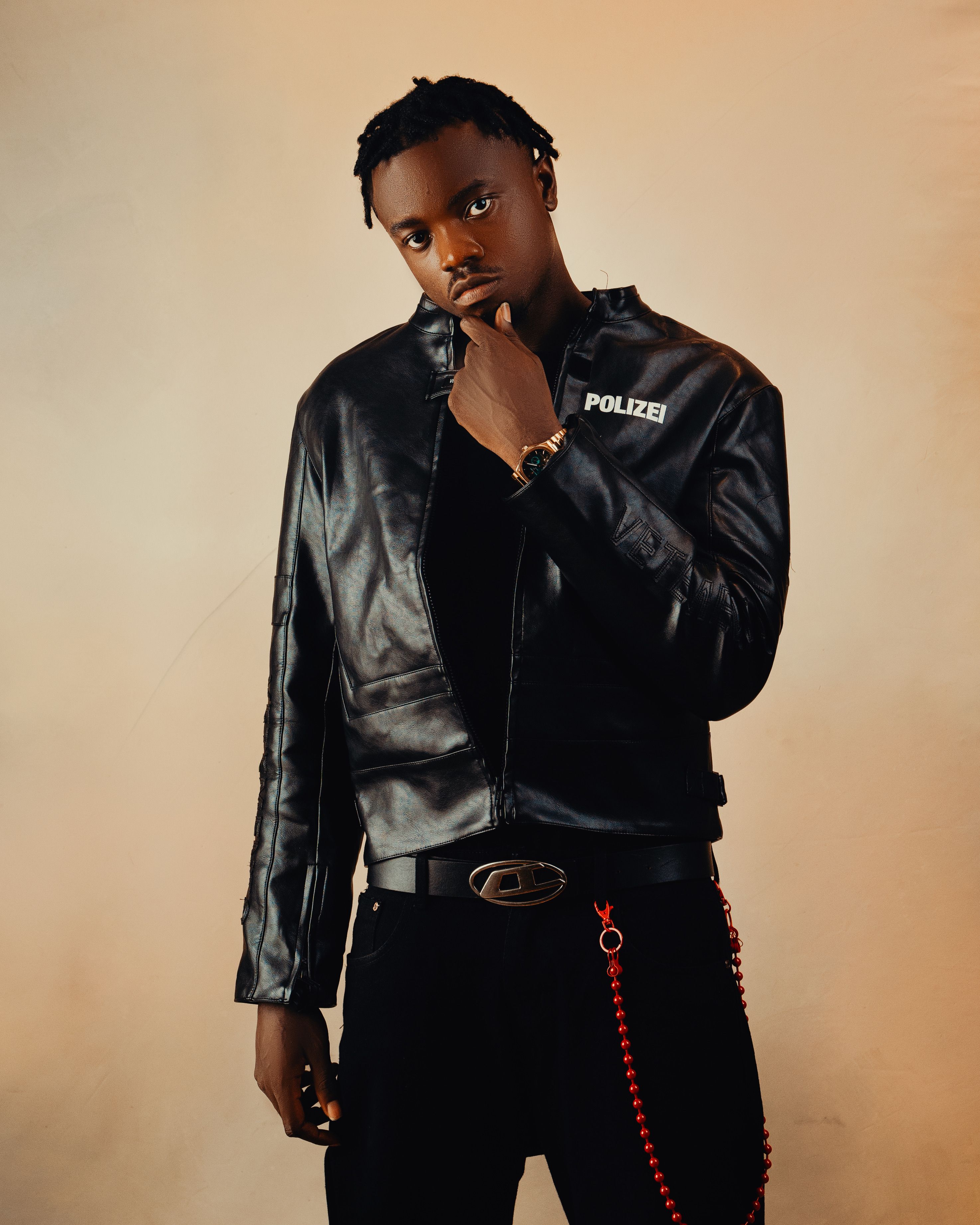 Fashionable man poses in a leather jacket with 'POLIZEI' text, exuding confidence.