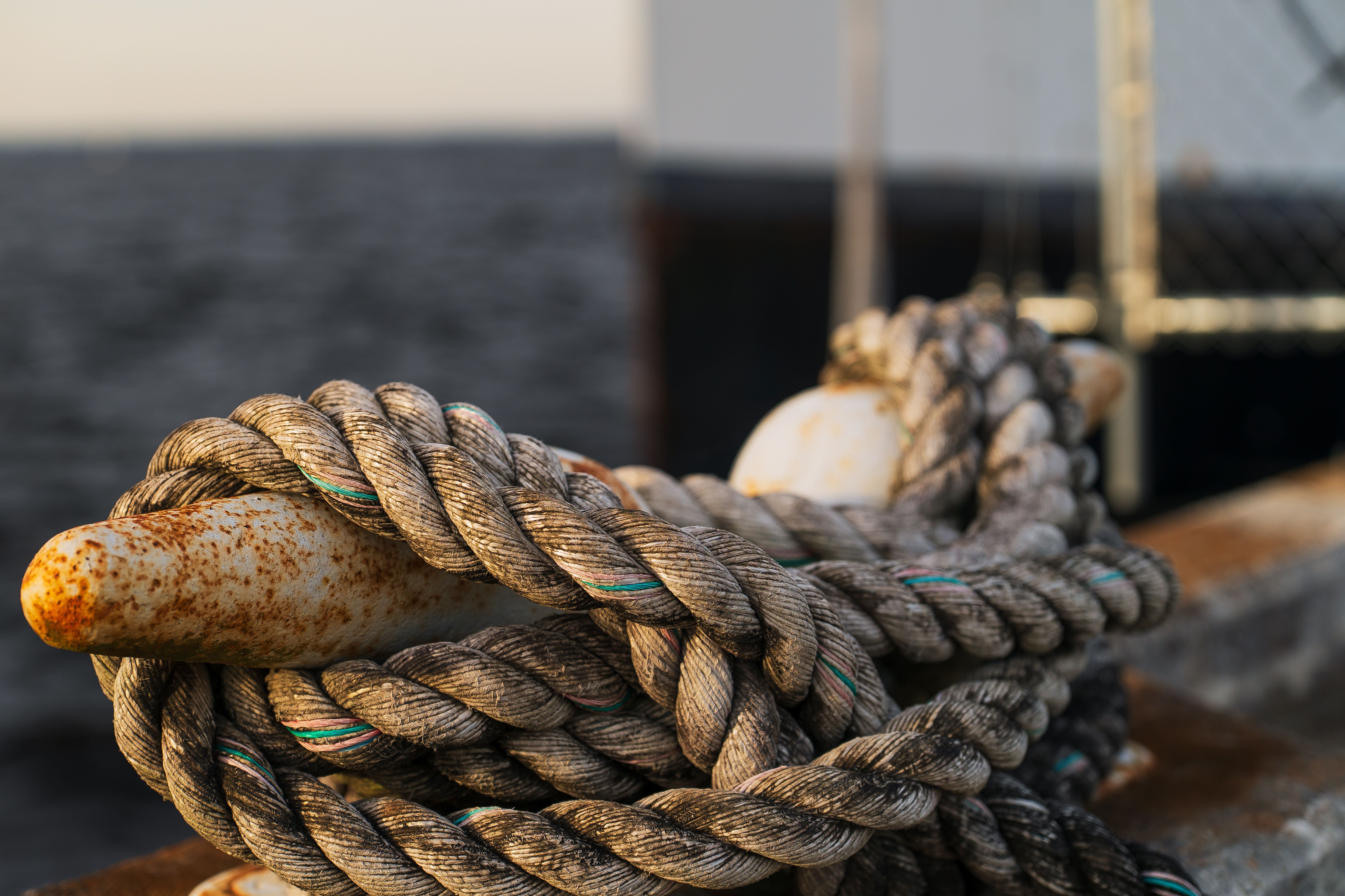 Rusty ship cleat with thick rope on dock, capturing nautical details and texture.