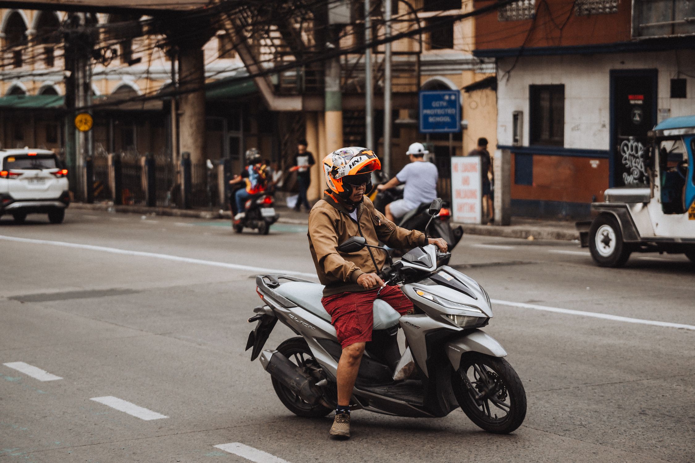 Man Riding Moped Man Riding Scooter in Urban Street Scene · Free Stock Photo