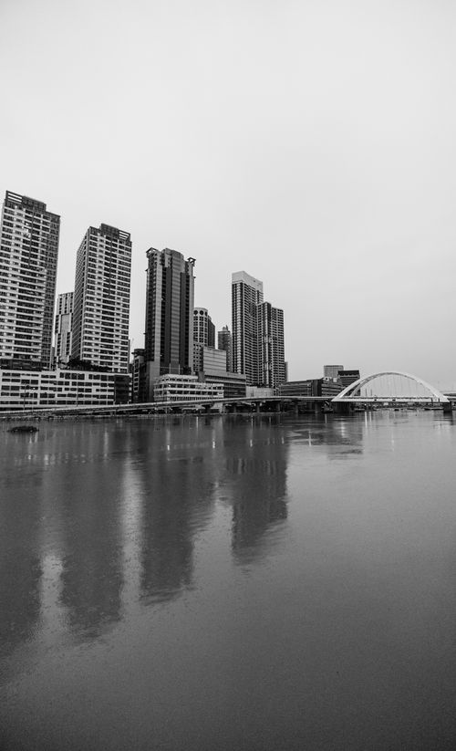 Free Black and white photo of high-rise buildings reflecting in a calm river. Stock Photo