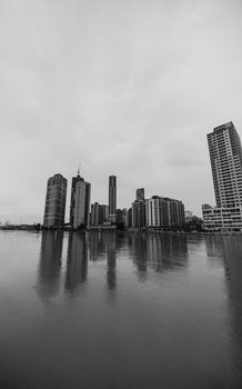 Black and white cityscape featuring tall buildings reflected on water, creating a calming urban scene.