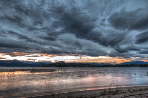 Free Captivating view of a dramatic cloudy sunset over a tranquil lake, reflecting vibrant colors. Stock Photo