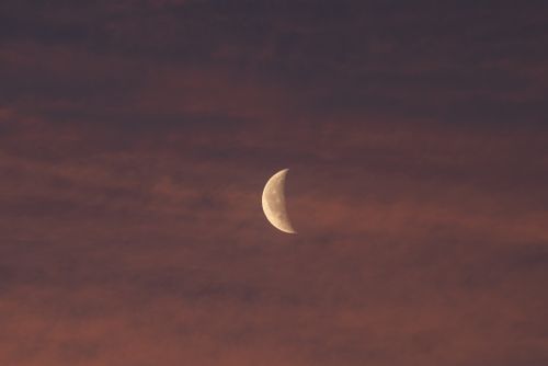 Free A crescent moon illuminated against a dramatic twilight sky with muted colors. Captivating night scene. Stock Photo