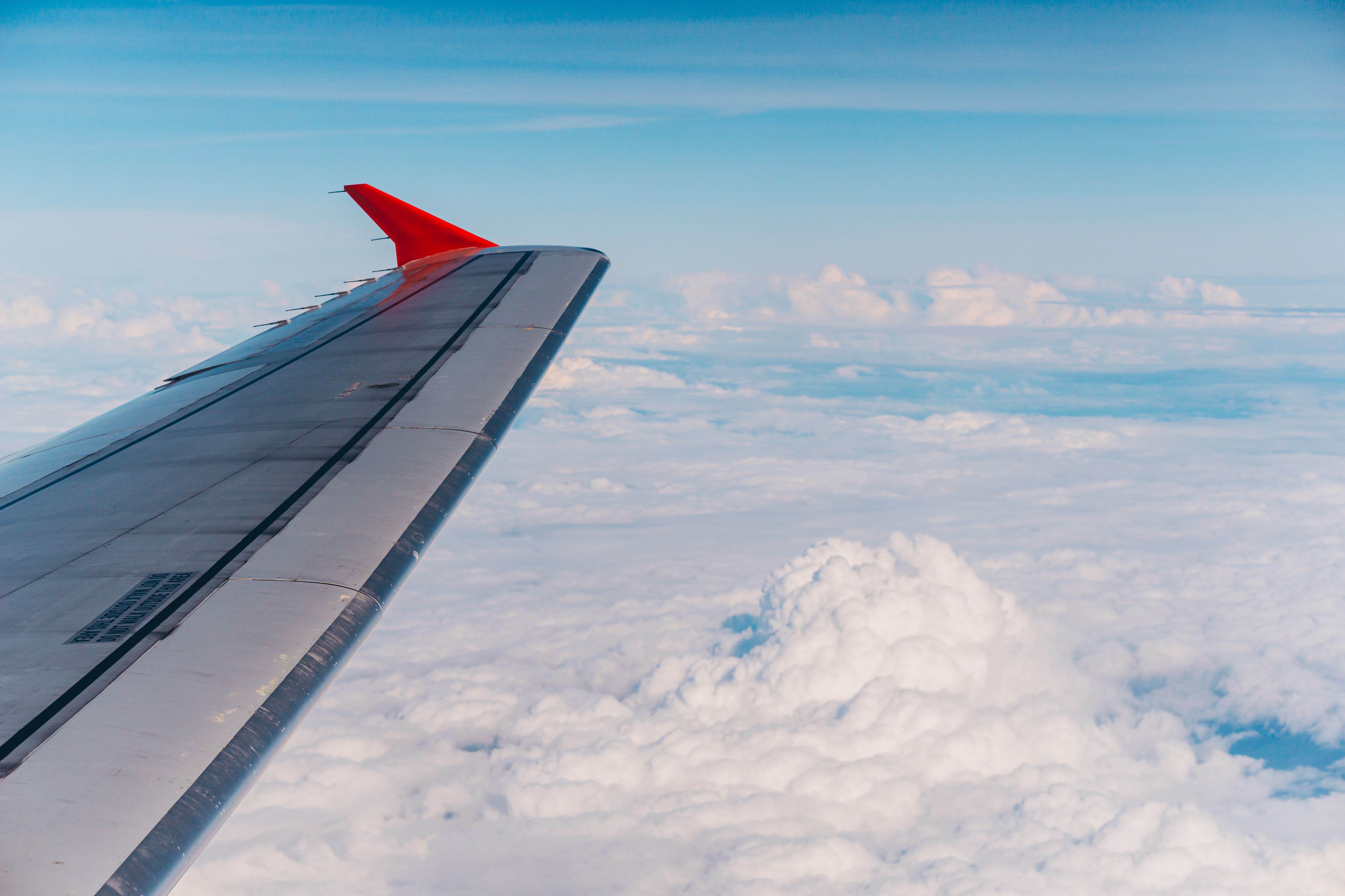 Wing of airplane flying over clouds · Free Stock Photo