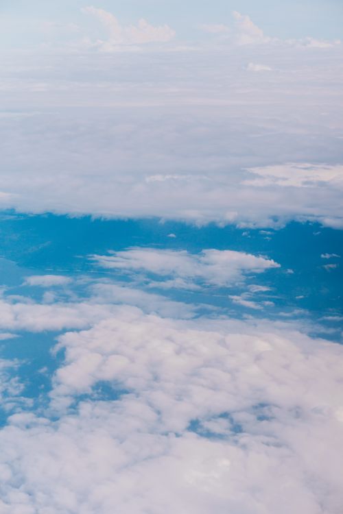 Free High-altitude view with fluffy clouds and vibrant blue sky, perfect for travel or nature themes. Stock Photo
