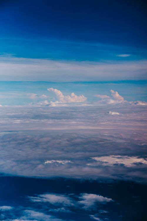Free A breathtaking aerial view capturing layers of fluffy clouds beneath a perfectly blue sky during the day. Stock Photo