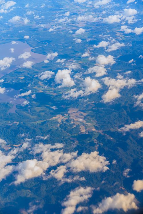Free A beautiful aerial shot showcasing fluffy clouds floating over diverse landscapes and water bodies. Stock Photo