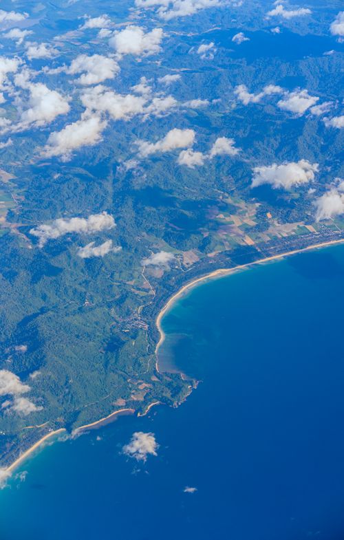 Free Beautiful aerial view of coastline, mountains, and clouds on a clear day. Stock Photo