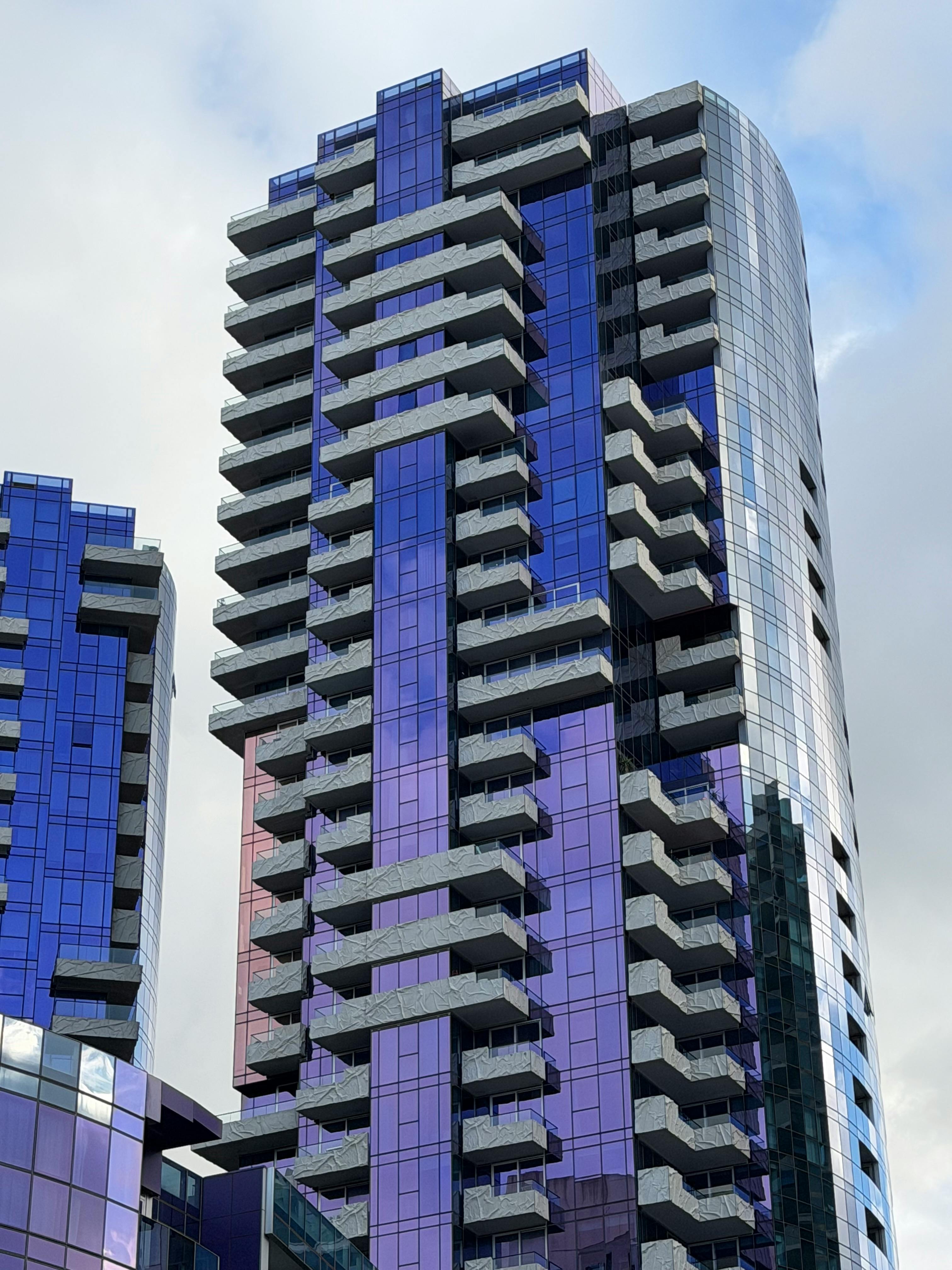 Stunning modern skyscraper with glass facade and angular balconies in Docklands, Melbourne, Australia.
