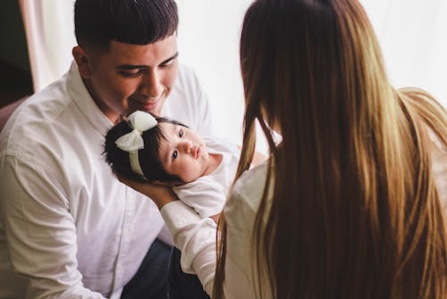 Woman Carrying Child in Front of Man