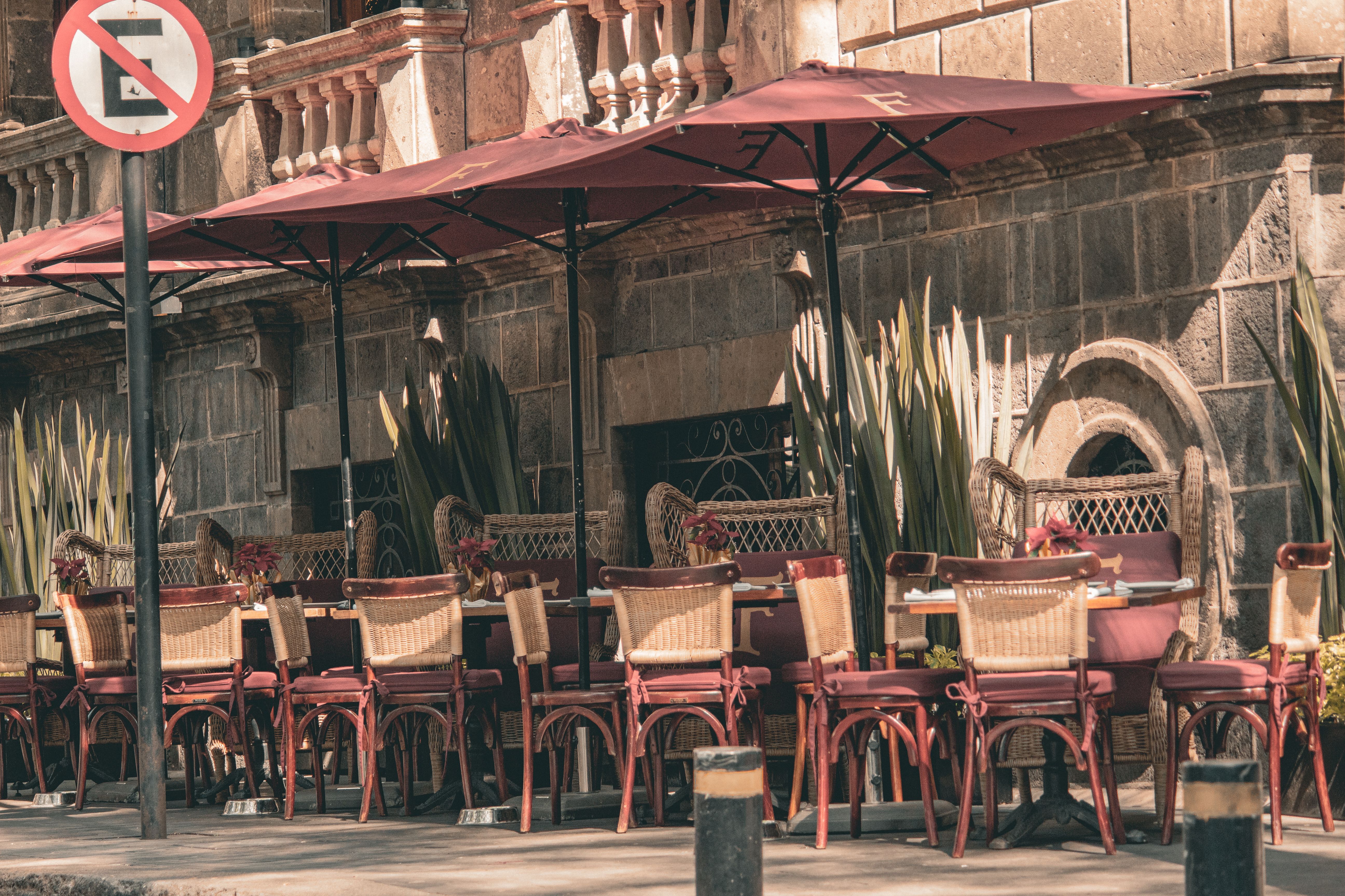 Sunlit outdoor cafe with red umbrellas and chairs in Ciudad de México