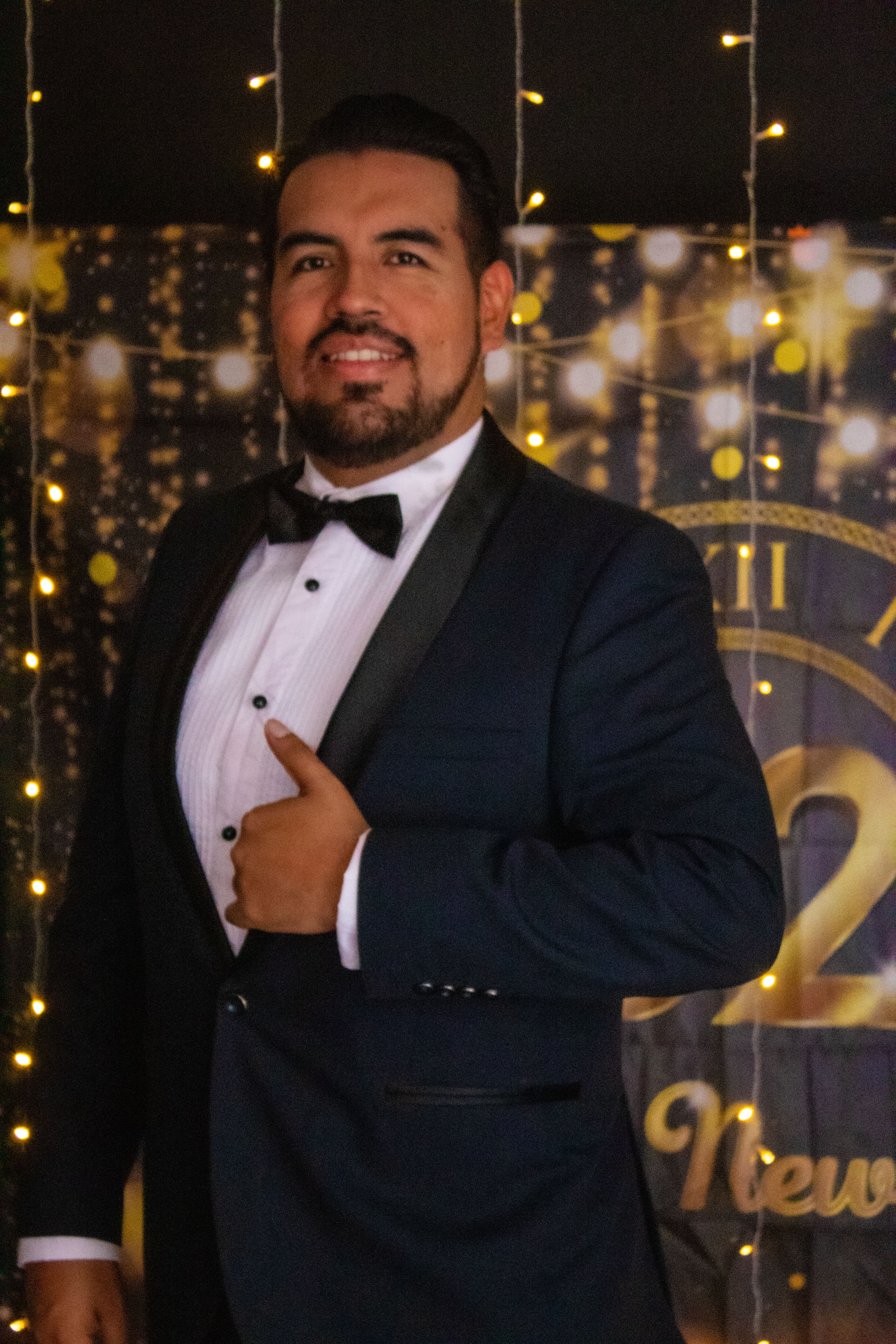 Smartly dressed man in tuxedo posing at festive New Year's event.