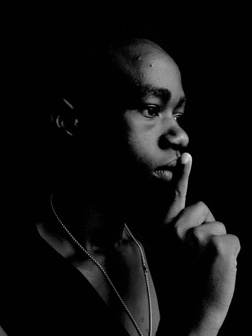 Free Black and white portrait of a man with finger on lips, symbolizing silence. Stock Photo