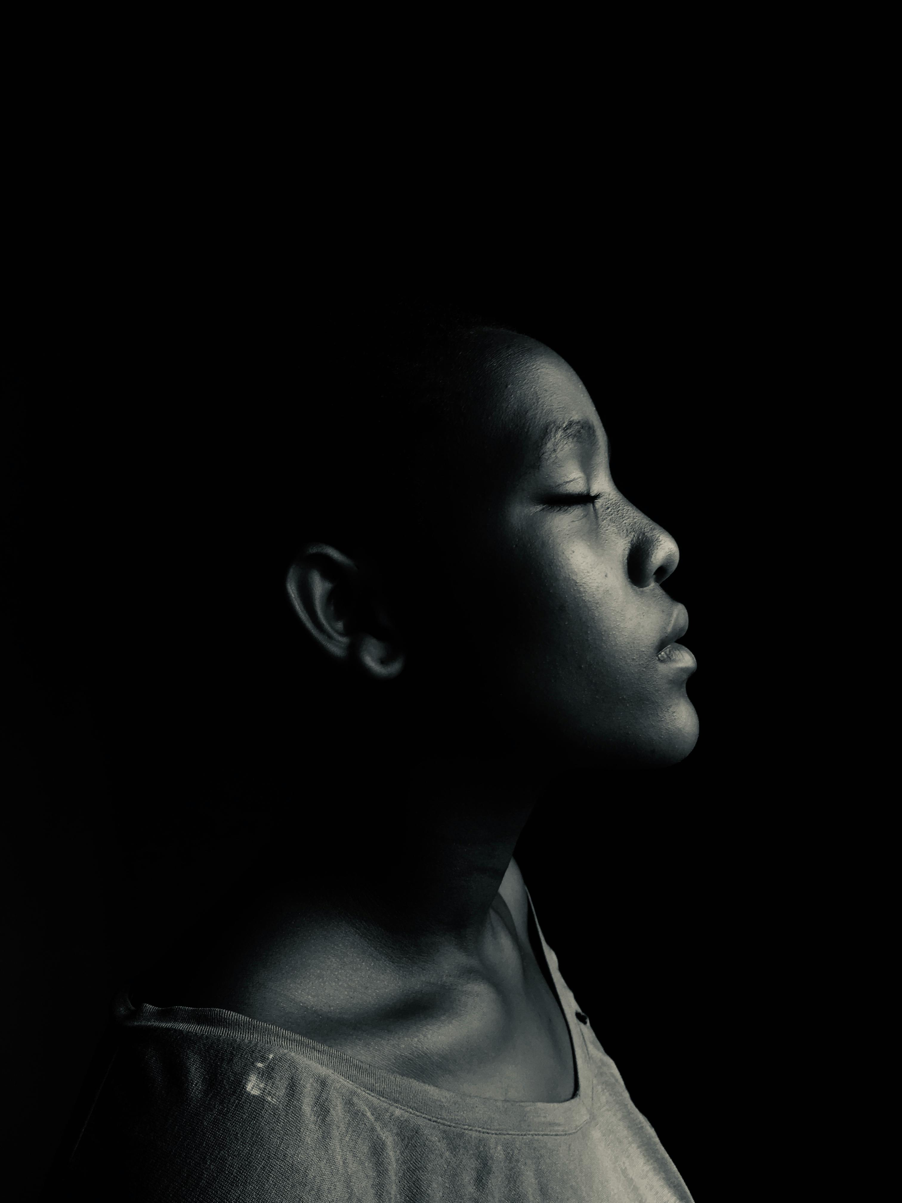 Artistic black and white side-profile portrait of a serene woman with closed eyes.