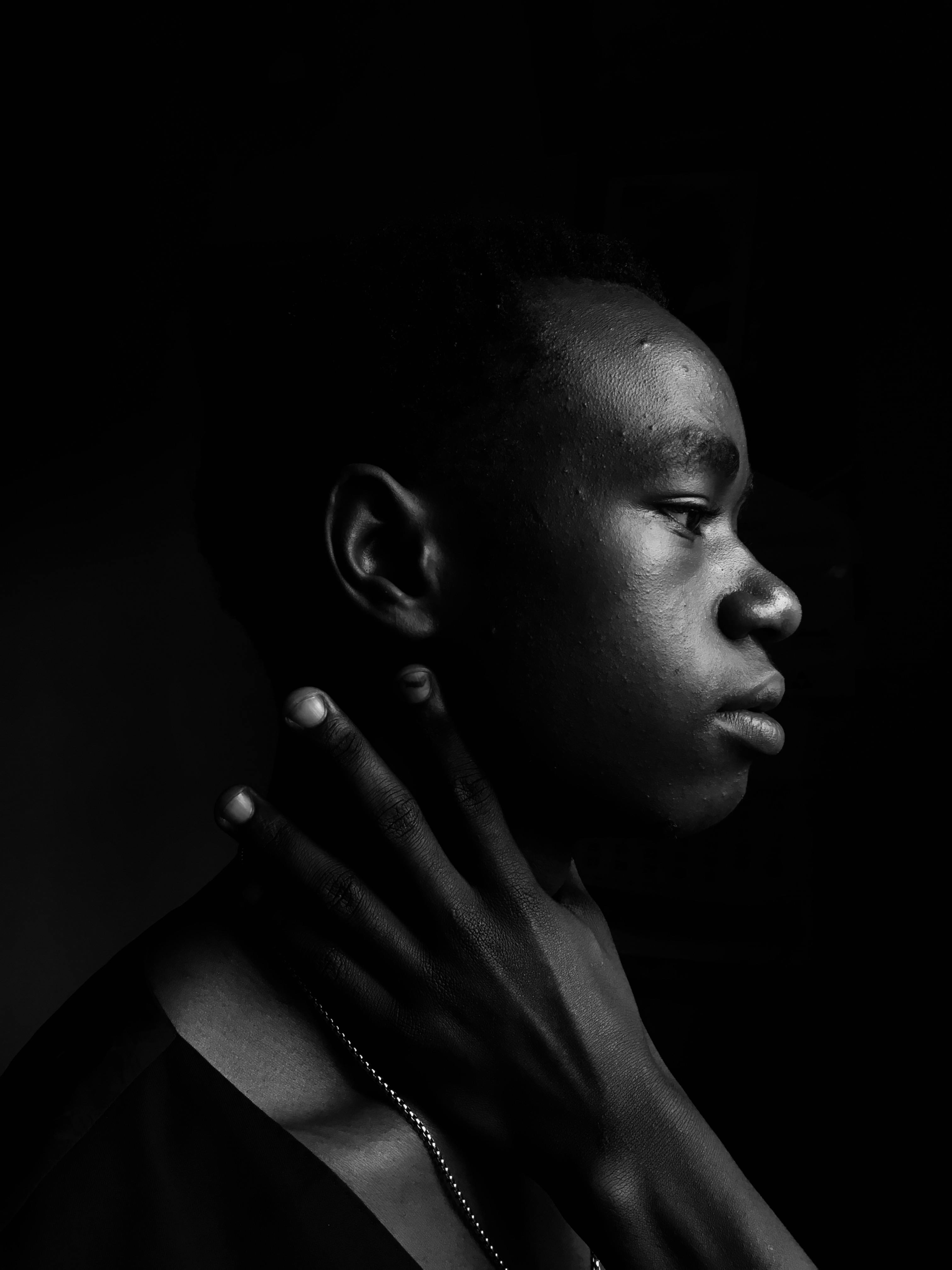 A striking side profile portrait of a young man in dramatic black and white lighting.