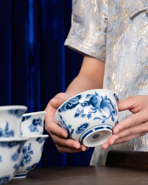 Free Close-up of hands holding decorative blue and white ceramic bowls on a wooden table. Stock Photo