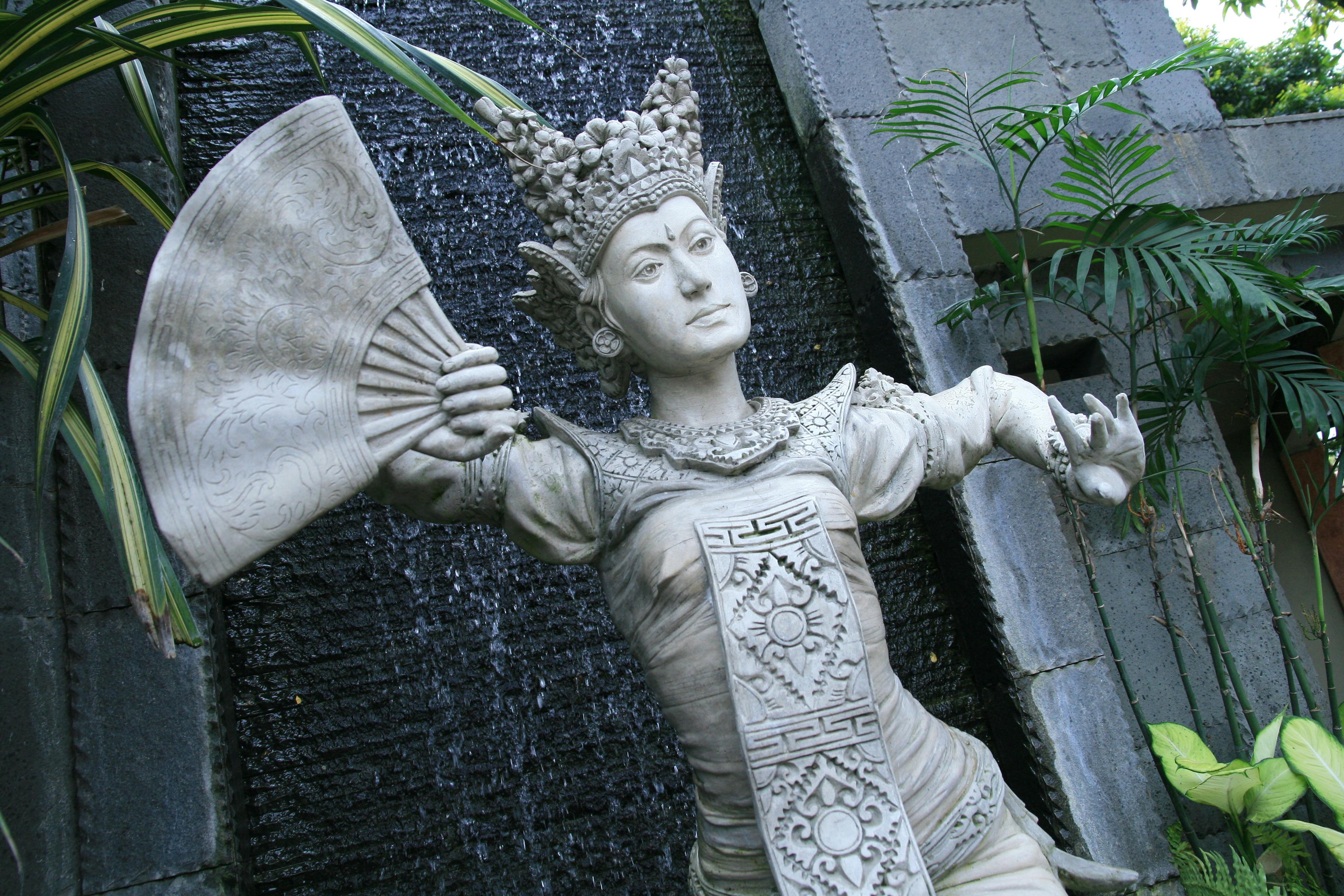Bezpłatne Misterna kamienna statua balijskiej tancerki z wachlarzem, umieszczona na tle przyrody w Bandungu w Indonezji. Zdjęcie z galerii