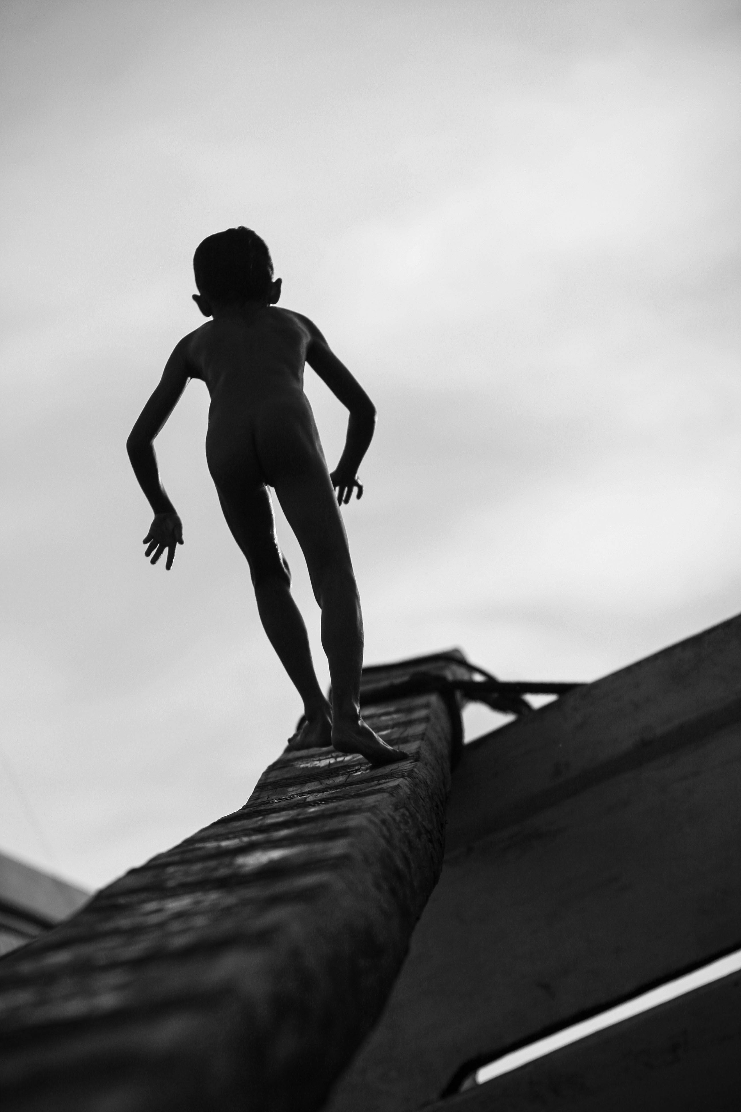 Gratuit À Sunda Kelapa, à Jakarta, un enfant se détache en silhouette sur une échelle, créant une scène saisissante. Photos