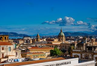 Discover the vibrant skyline of Palermo, Sicily capturing historic architecture beneath a bright blue sky.